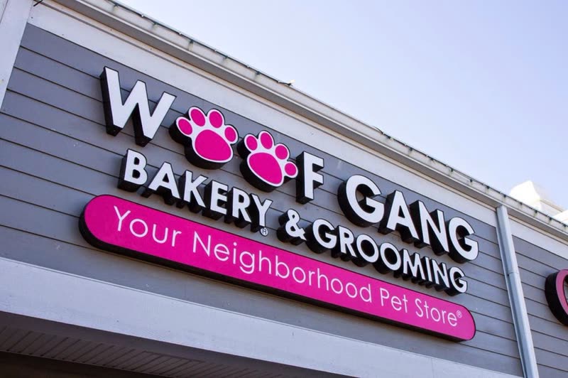 The Woof Gang Bakery & Grooming storefront sign with its pink paw-print logo
